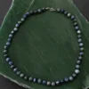 Colar de cianita azul natural em bolas sobre fundo quartzo verde.