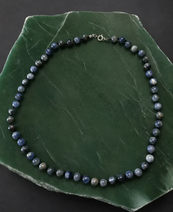 Colar de cianita azul natural em bolas sobre fundo quartzo verde.