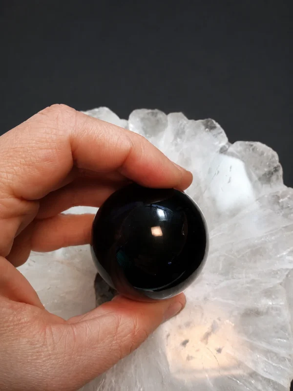 Esfera obsidiana negra natural com 5 cm de diâmetro exibida na mão.