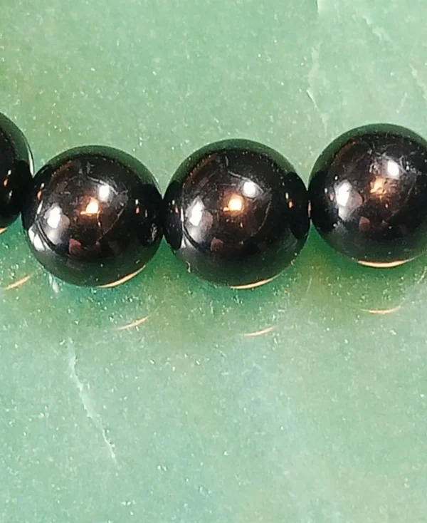 Detalhe das contas de Azeviche natural 8 mm com acabamento polido e superfície lisa.